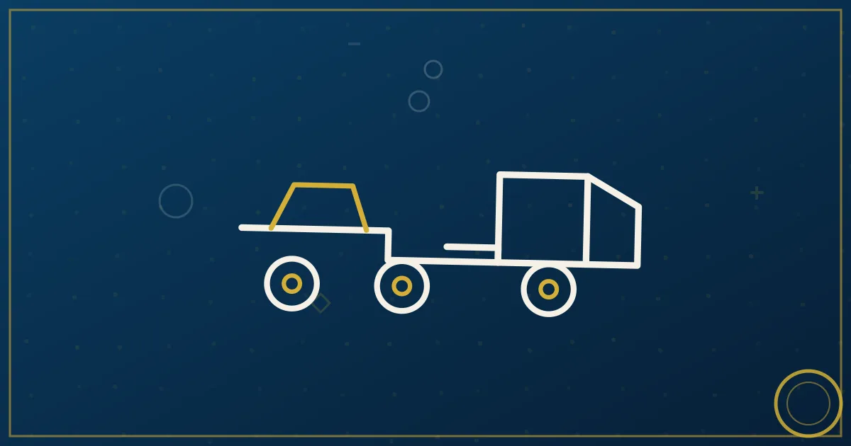 Step-deck trailer carrying a yellow excavator secured with chains on a rural highway